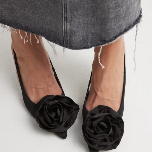 Svarta pumps med ros - Svarta pumps från NA-KD med ros framtill. Endast använda 1 gång, storlek 37.