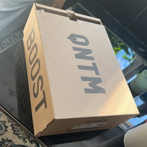 Adidas Yeezy QNTM - Ett par Adidas Yeezy QNTM (flash orange)sneakers med en unik design i flera färger inklusive svart, grå och orange. Skorna har en hög ankel och en robust sula. Nya, bara uppackade å testade!