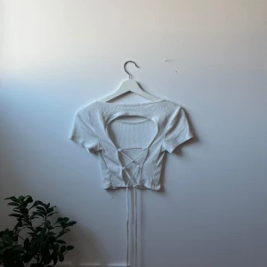 Vit t-shirt - Vit, lite kortare t-shirt med öppen rygg och snörning som man kan knyta beroende på hur man vill att tröjan ska sitta.