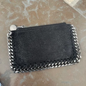 Stella McCartney plånbok - Jag säljer min svarta Stella McCartney plånbok, då jag fått en ny plånbok. Den är i perfekt skick och inga skador! 