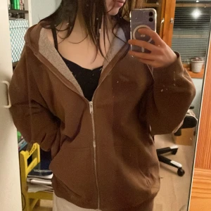 Baggy oversized brun zip-hoodie - Brun hoodie i oversized fit från Brandy Melville. Hittade inte storlek men den är 72 cm axel till axel och 73 från axel till nederkant. Passar bekvämt och oversized på mig som är storlek s. Väldigt bra skick och rejält, bekvämt material. Köpt för 470