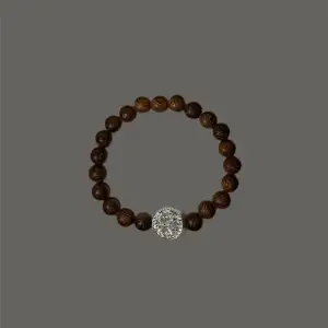 Pärlarmband med bruna träpärlor och en silvrig mellandel (livets träd). Demeter är ett stilrent armband som passar såväl till vardags som till festligare ögonblick. Armbandet har en omkrets på cirka 19 cm.