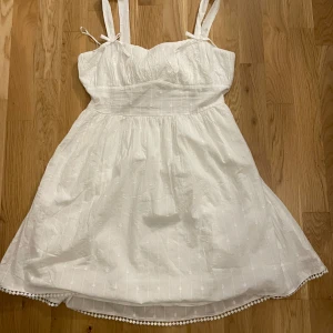 vit klänning med rosettdetaljer - köpte denna superfina klänning till studenten, men har nu hittat en jag gillade mer😊 har enbart provat den! den är  justerbar i storleken på grund av rosetten baktill:) eftersom den är ny säljer ja den för fullpris:)