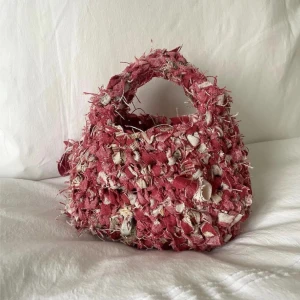 Unik virkad väska - Väska vrickad av tygrester. ♻️ca 23x20 cm stor. Virkad av ett robust möbeltyg från Italien. Rymmer en mobil, plånbok och nycklar. Allt som man behöver. Små rosetter knutna på diverse ställen. Svarar gärna på frågor.