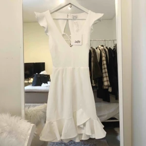  - Vit klänning som är perfekt för student eller avslutning. Den har en superfin snörning i ryggen och en v-ringning i fram. Väldigt bra och fint material på klänningen. 