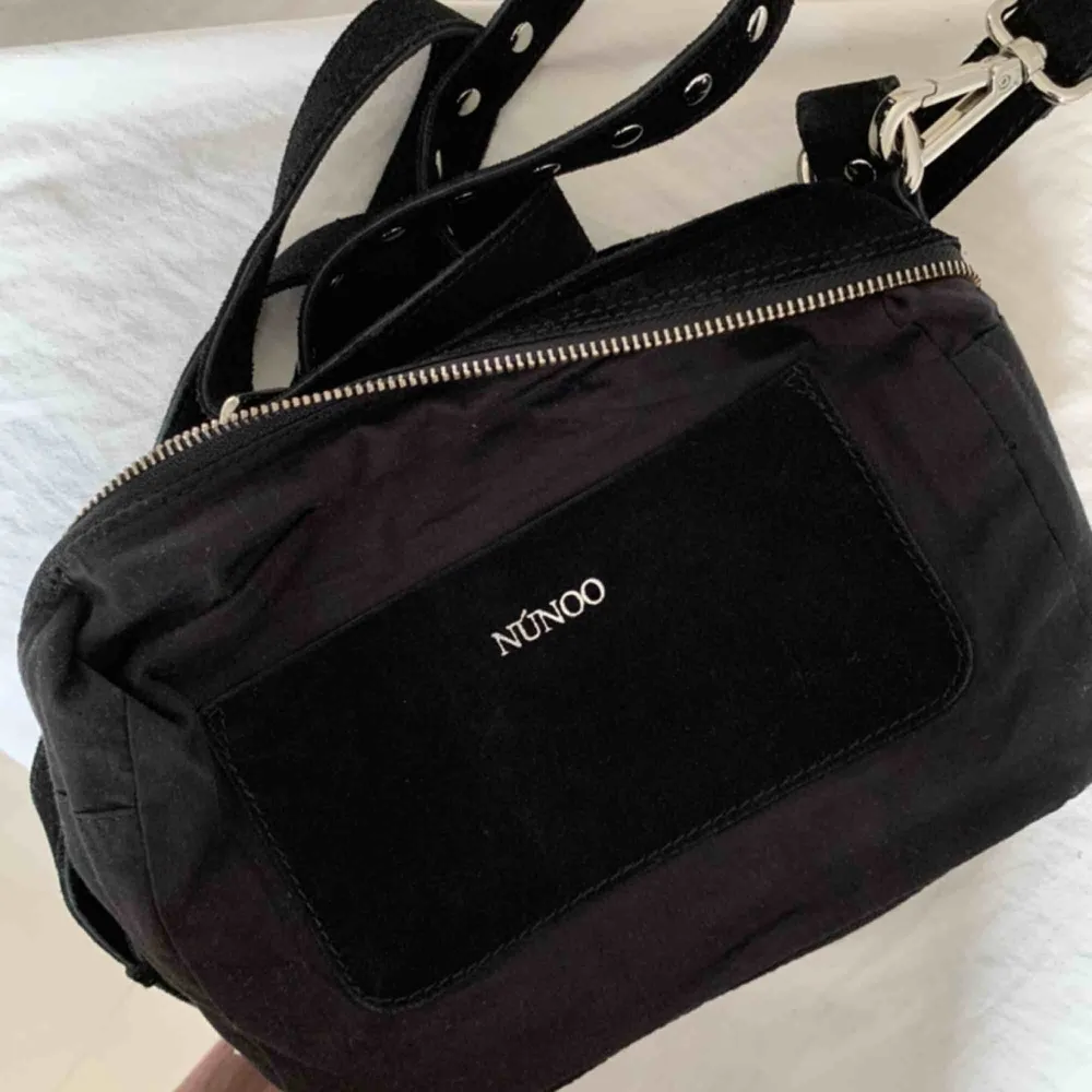Svart NuNoo väska i modellen ellie new suede.  Inköpt för 4 veckor sedan och använd ett fåtal gånger. Långt axelband medföljer. Nypris: 1400 kr . Väskor.