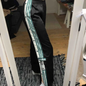  - Adidas byxor med knäppning på sidan. Bra skick, tyget är lite upprivet på ena benet men det är inget som syns. Original pris: 800kr. Spårbar frakt inkluderat i priset💞