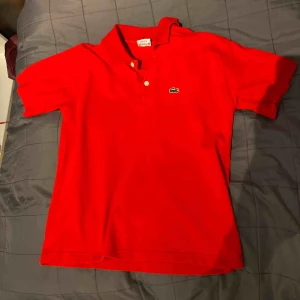  - Röd Lacoste i bra skick med grön logga Stl. M 