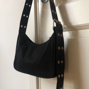 Svart väska från weekday - Svart mini väska från weekday med fina detaljer. Använd några få gånger. Bandet går att förlänga och förkorta.