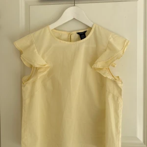 Ljus top med vloang - Ljus gul top med vloang över Axel ifrån Lindex. Stl 36
