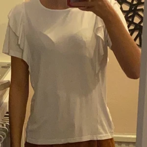 Vit t-shirt med detaljer - Säljer en vit t-shirt med detaljer på armarna. Köparen står för frakt eller så kan vi mötas upp.💕
