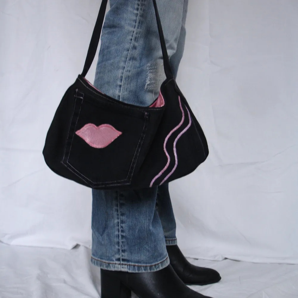 Handsydd svart jeansväska med rosa insida som matchar applikationerna. En ytterficka och en innerficka med dragkedja. . Väskor.