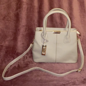 Grå Handväska med guld detaljer. ✨ - Vintage ljus grå väska, med guldiga detaljer. Avtagbart band. Svart insida med 2 fack. Använd. 👼🏼✨ 