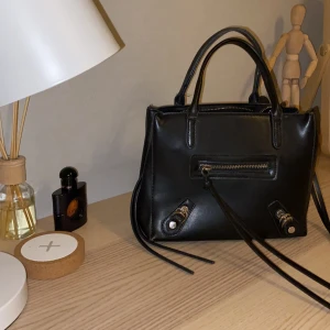 Nelly väska - Super snygg och praktisk väska från NELLY! I toppen skick och är väldigt rymlig. Finns även två mobilfack och en dragkedjeficka på insidan och en på utsidan 🤩 Långt band medföljer 