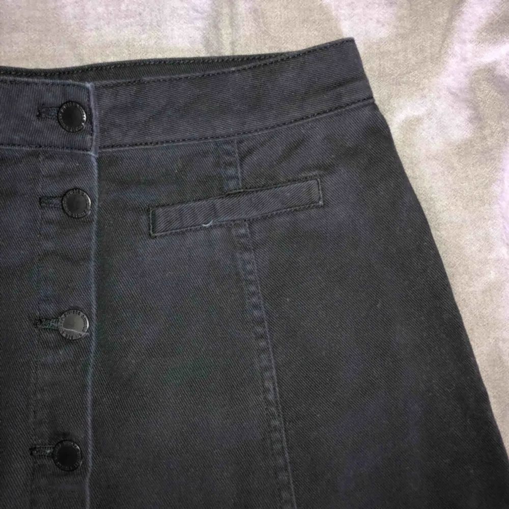 Fin svart jeans kjol med knappar och fusk fickor på vardera sida, kjolen kommer från hm och är använd högst 3 gånger. . Kjolar.