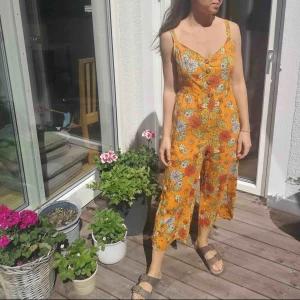  - Blommig färgglad byxdress med justerbara axelband. Perfekt för sommaren 