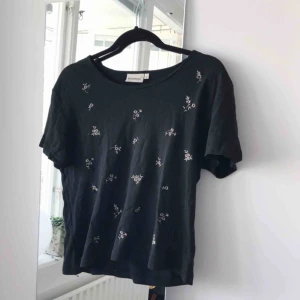  - Supersöt svart T-shirt med guldiga blommor broderade på framsidan. Frakt ingår!