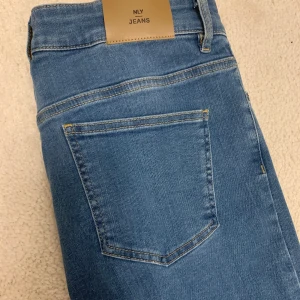 NYA: Superstretch High Waist Denim/ NLY Jeans/ 42  - Sprillans nya jeans från NLY Jeans. Aldrig använda. Lukten av nya jeans finns fortfarande kvar. Modellen är superstretch high waist denim i storlek 42, men passar även 44 då de är så stretchiga. Säljes då de är för stora för mig. Tveka inte att höra av dig vid frågor! :)
