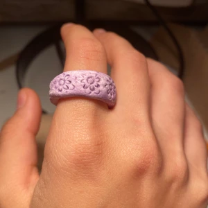 Lila ring  - Keramik ring, hand gjort med blommor på. Tål inte vatten men man kan ba måla på genomskinligt nagellack, problem löst. Frakt tillkommer eller hämtas i Malmö. 