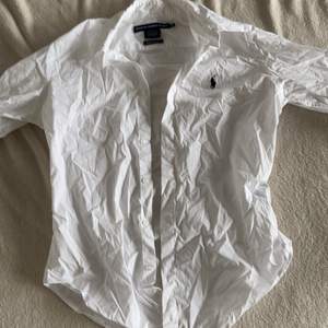 Vit Ralph Lauren skjorta med ärmar som slutar innan armbågen. Har sömnad anpassad för kvinnlig figur.