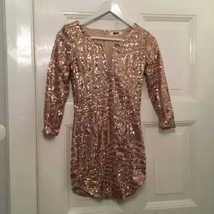 Aldrig använd guld/rosé guldig paljettklänning från DM retro.   Säljer för den är alldeles för kort för mig. Prislapp sitter kvar och har sparat påse också. Frakt tillkommer.