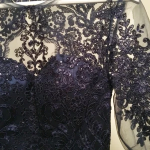  - En mörklblå klänning med mörkblå paljetter uppe till, armar i spets samt öppen i ryggen. Klänningen har endast använts en gång och det va på studentbalen. Storlek 36, kanske lite stor i storleken. Frakt tillkommer.