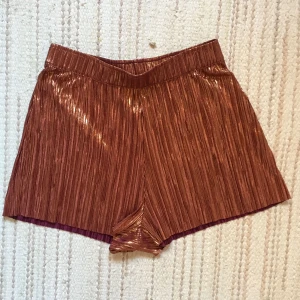  - Oanvända plisserade shorts som man kan ha åt båda håll, antingen kopparglittriga eller plommonlila. Superfina!