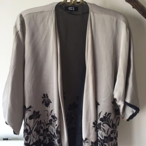  - Grå-beige aktig kimono från bikbok. Köpt den på tradera men aldrig använd. Står XS men det är mer en S (liten M).   Garderobsrensning, se mina övriga annonser.   Köparen står för frakt. Ansvarar ej för postens ev slarv.