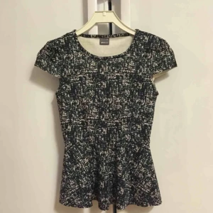  - Peplum topp i svart-vitt-grått mönster. Från Gina Tricot. Fint skick och knappt använd.