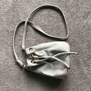  - Suede premium väska i färgen ljusgrå med guld detaljer. Frakt tillkommer på 50kr