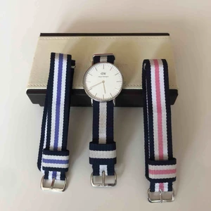  - Tre Daniel Wellington armband och klockan. Allt har silverdetaljer. Blått, lila och rosa armband. Klockan går självklart att flytta till önskat band. 36mm på alla band. Använda men inte slitna.