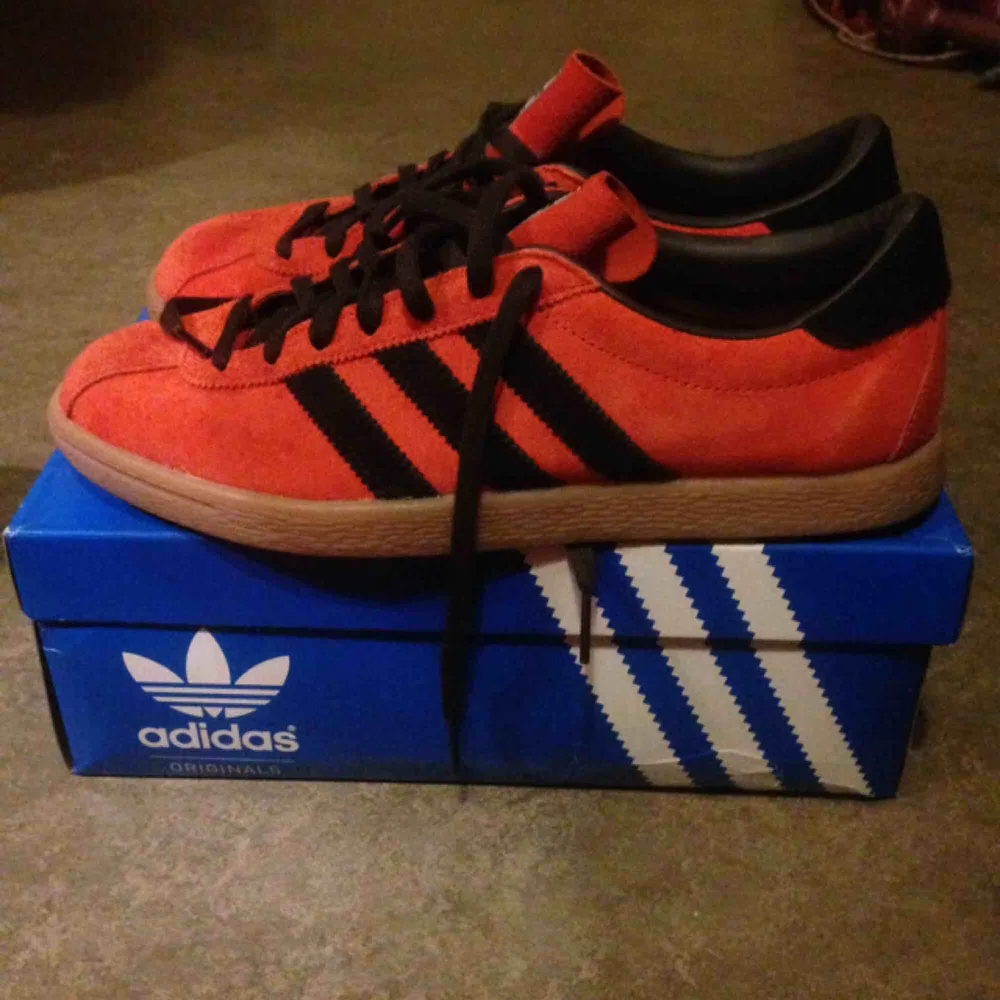 Orange Adidas skor, helt oanvända. Finns i Sthlm, kan även skickas då köparen står för frakt.. Skor.