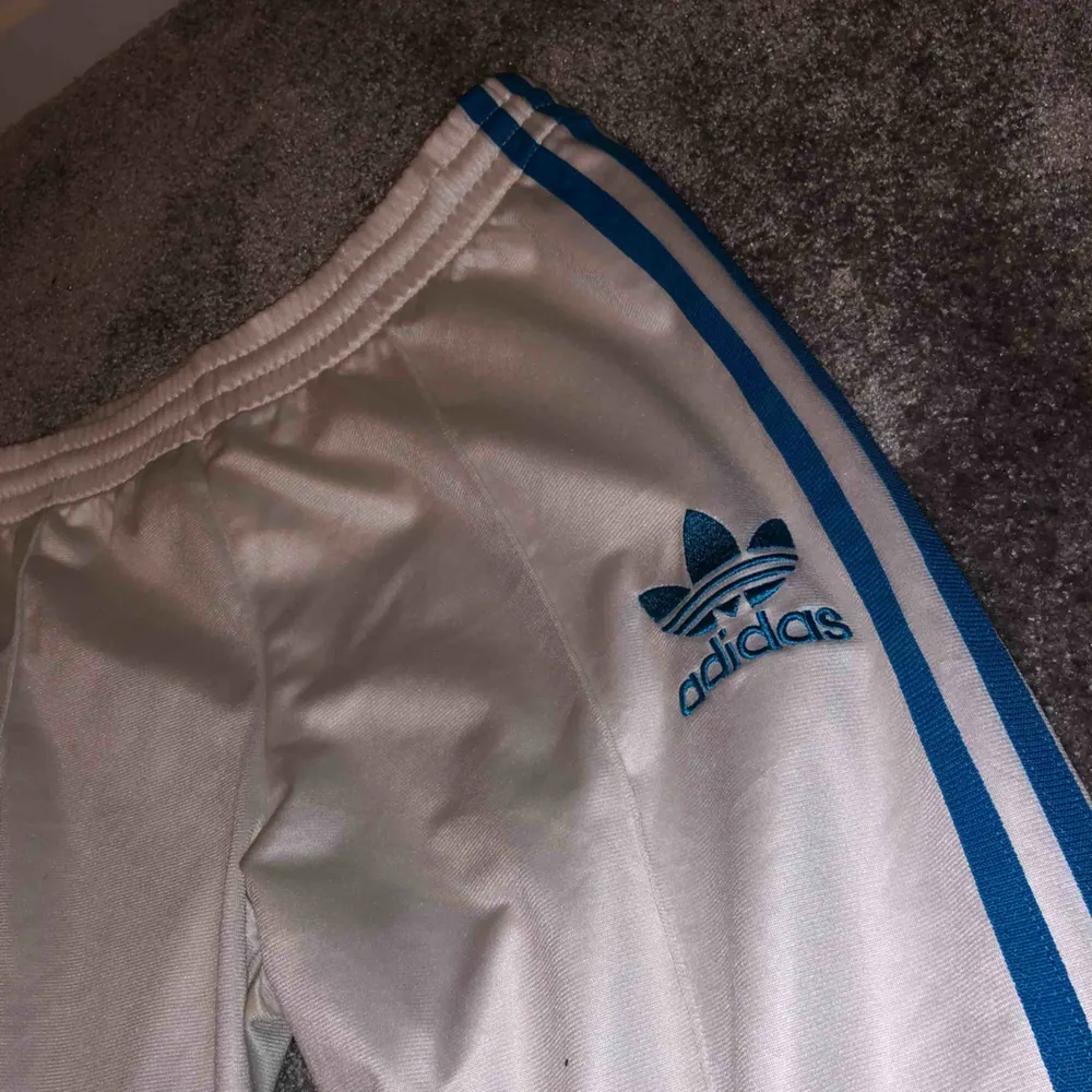 vita Adidas byxor med blåa streck, dom har en lite fläck där bak (se bild) har inte testat å tvättat så kanske går bort annars mkt fint skick✨. Jeans & Byxor.