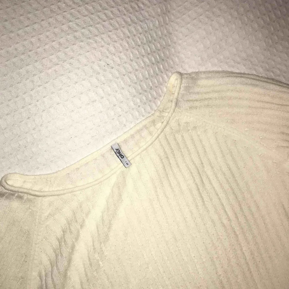 Gräddvit ribbad tröja med slits från Only. Tröjan är rätt genomskinlig, jag brukar ha ett vitt linne eller bralette under. Endast använd fåtal gånger.🌸. Toppar.