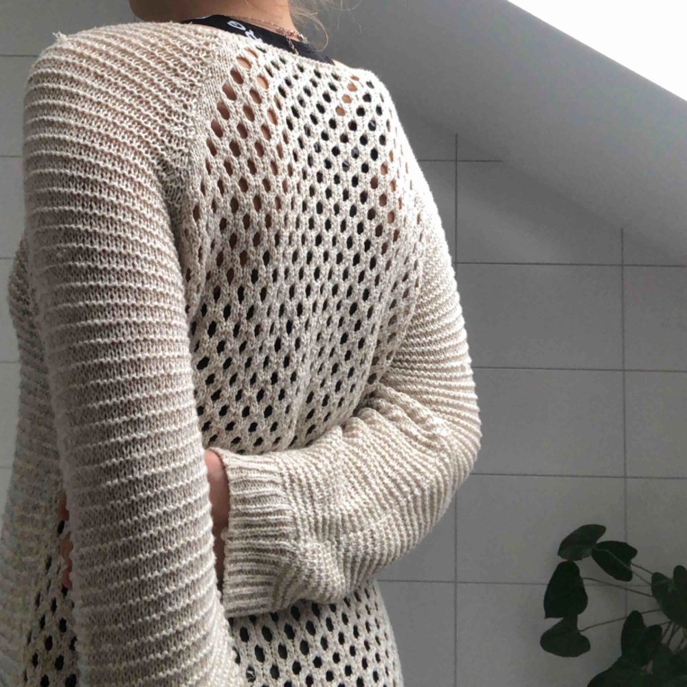 En stickad tröja med ”hålmönster” på baksidan. Lite längre baktill för att täcka rumpan. Skönt och mysigt material i en sand/beige färg! . Stickat.