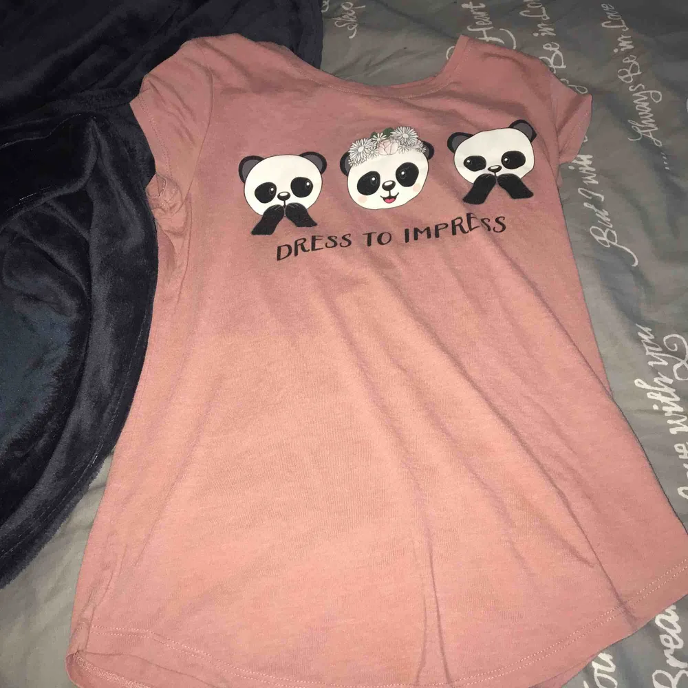 En rosa t-shirt med ett tryck där det står ” Dress to impress “ storlek S men passar en xs enligt mig  Plagget är från newyorker . T-shirts.