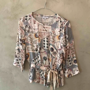  - Mönstrad blus med knyte i midjan. 