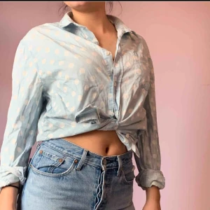  - Ljusblå skjorta med stora vita prickar🦋 Går att stylea på olika sätt tex knyta eller ha den öppen med en snygg topp under💫🤩 Är tyvärr sönder i vänstra kanten men går enkelt att följa om man knyter den😉🤟🧞‍♂️