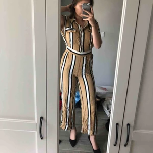Jumpsuit - Superfin randig jumpsuit som är från bikbok. Resår i midjan, knäpps upptill med knappar och har även 2 fickor på brösten. Är med beige/brun i verkligheten. Använd endast 1 gång😊 100kr + frakt