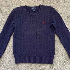 Polo Ralph Lauren marinblå Kabelstickad - Marinblå kabelstickad tröja från Ralph Lauren i bra skick. Storlek 14-16 ÅR
