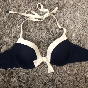 Twillfit bikini marinblå - jätte bekväm bikini från twilfit, knappt använd pga att det är för liten för mig, har 70B/C i bh st. Bygel under brösten, klämma i ryggen och knyt i nacken, även en fin knyt detalj mellan brösten. Frakt ingår ej, kan mötas upp i karlstad vid intresse :) 