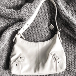 Axelbandsväska vit - hej! detta är en rätt så gammal väska och är därför inte i nyskick! den har synliga fläckar på insidan men den är helt ren! kontakta gärna vid intresse och FRAKT ingår INTE i priset!