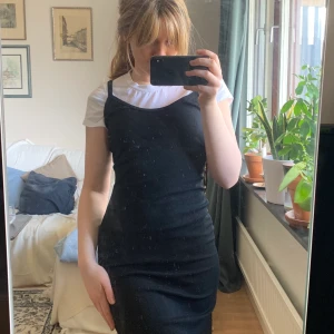 Långklänning - Svart ribbad långklänning som aldrig blivit använd, prislappen från Humana sitter kvar. Storlek står inte men den är mycket tight så skulle säga XS-S. Lång slits i mitten bak! (vit t-shirt ingår inte) 