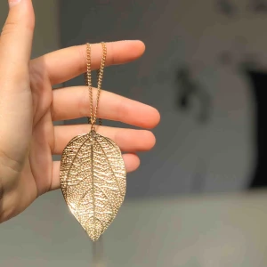  - Ett fint, tunt löv i guld med en tunn guldkedja.  