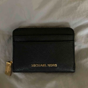  - Svart Plånbok med guld detaljer! Köpt på Michael Kors butiken för 1100kr! 11 cm bred x 9 cm hög Hör av för fler bilder! Den är såklart äkta, ska leta upp kvittot! Säljer då den aldrig kommit till användning för min del! Fraktar ej!  Möts upp i Stockholm!