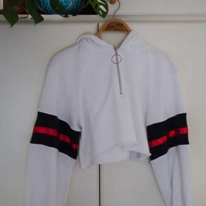 Bekväm vit hoodie med röda&svarta detaljer, högmidjad & luva. Från märket Boohoo. Status: Använd 1-2 gånger,dock små norpor på något ställe (bild 3) Från ett djur&rökfritt hem, frakt står köparen för. 