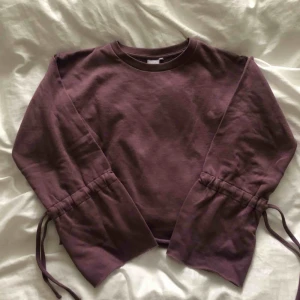  - Mysig tjocktröja i superfin lila färg med band som man kan dra åt ärmarna med. Klippt av tröjan själv för att få en bättre längd på den, skulle säga att den är lite kortare än normallängd. Fraktar endast, och ingår i priset🥰