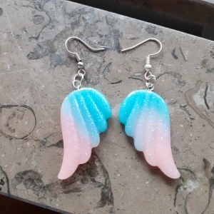 Söta örhängen - Fantasyörhängen i form av vingar💙Vackra pastellfärger i rosa/turkos/blå. Material: Acrylic. Silverpläterad kirurgisk stål. Märke: Sunshine wang tomorrow. Skick: Nya☆Frakt: 11:-