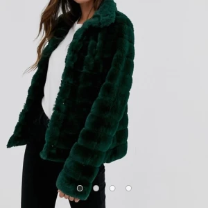 Mörkgrön jacka i fuskpäls - Aldrig använd jacka från Vila - Silkeslent foder - Cut away-krage - Tryckknappar - Funktionella fickor - Normal passform