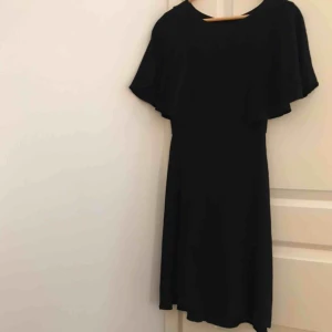  - Svart klänning med fladdriga ärmar och avtagen midja. Går ungefär till knäna på mig som är 162cm. Säljs då den inte används längre. Är i nyskick!